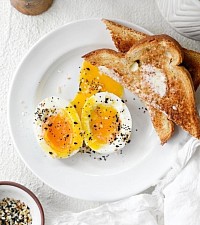 One medium hard boiled egg sided with a piece of toast and butter
