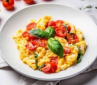 Fresh scrambled eggs with tomato and fresh herbs